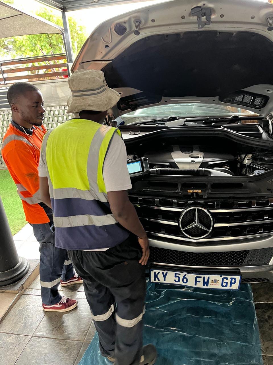Technicians inspecting an engine under a canopy